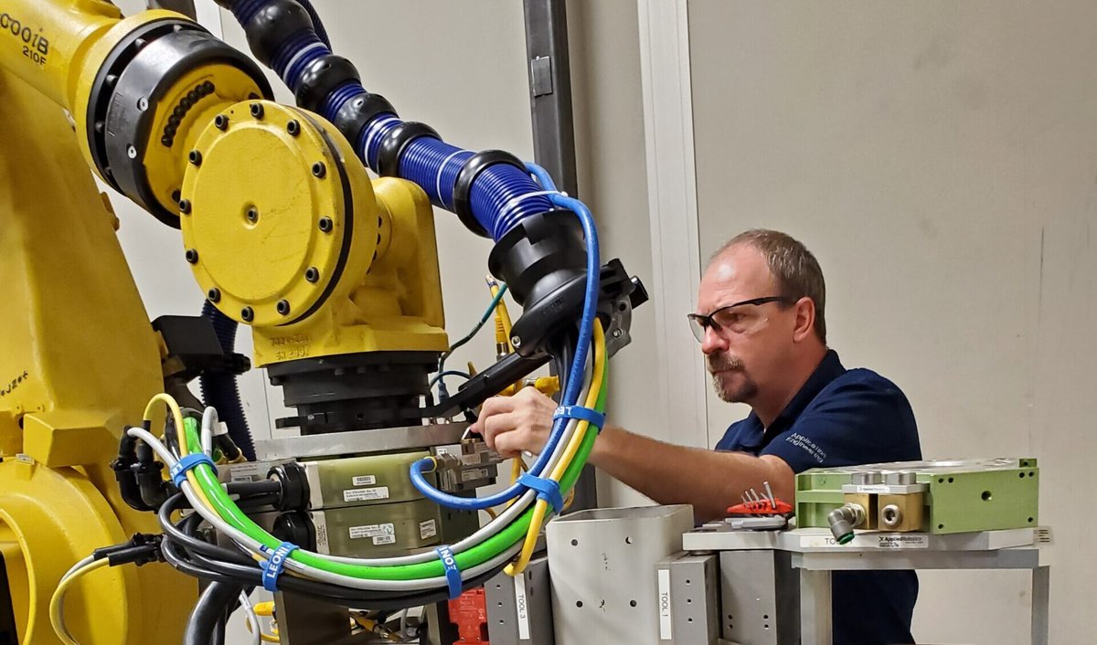 Un dipendente di Effecto sta lavorando su un sistema di cambio utensili e un robot, effettuando operazioni di manutenzione